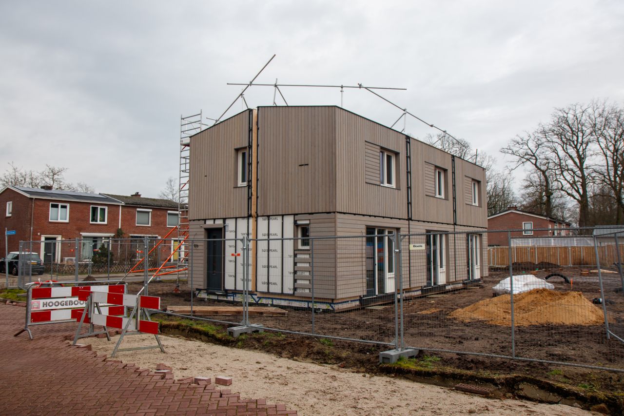 Sustainable Living Starts with Smarter Construction A modern house under construction with scaffolding, fences, and construction signs on a cloudy day.