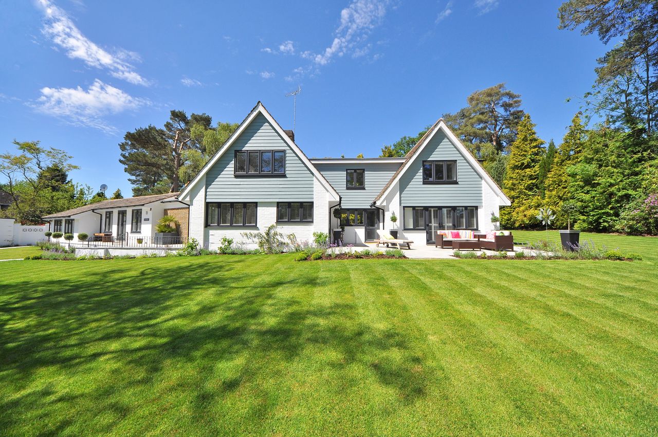 Why Modular Homes Are Becoming a Smart Real Estate Investment Modern family home exterior showcasing a large lawn and garden under a clear blue sky.